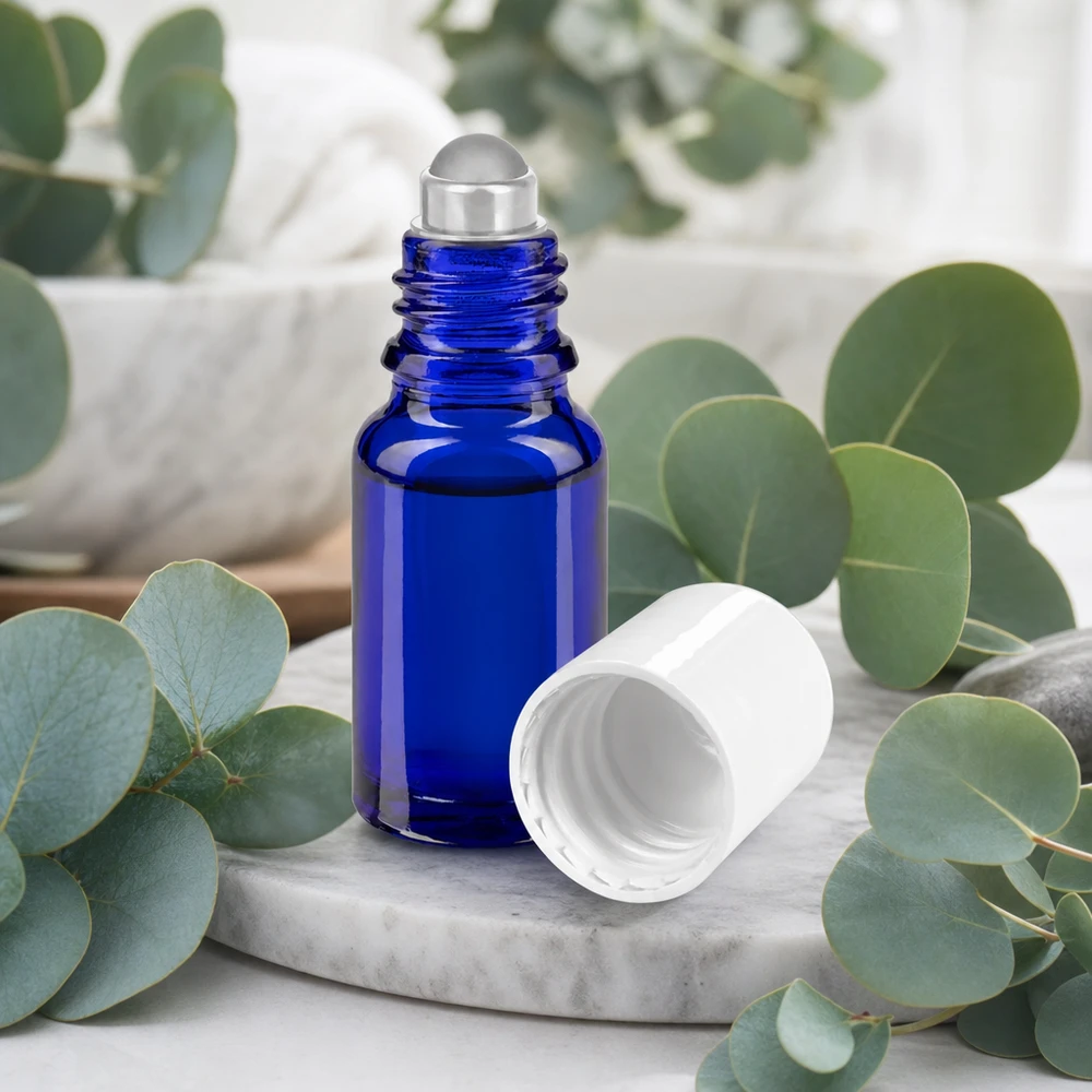 Apteekkipullo sininen 10ml roll-on korkki valkoinen Koboltinsininen 10 ml:n apteekkilasinen roll-on-pullo, jossa on ruostumattomasta teräksestä valmistettu rullapallo ja valkoinen korkki marmoripohjalla
