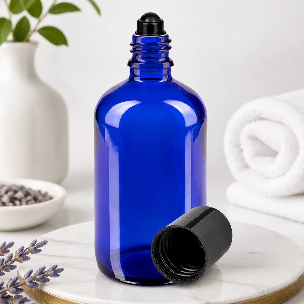 Apteekkipullo sininen 100ml roll-on korkki musta Sininen 100 ml:n lasipullo, jossa on musta rullapää ja irrotettu korkki, marmoripinnalla