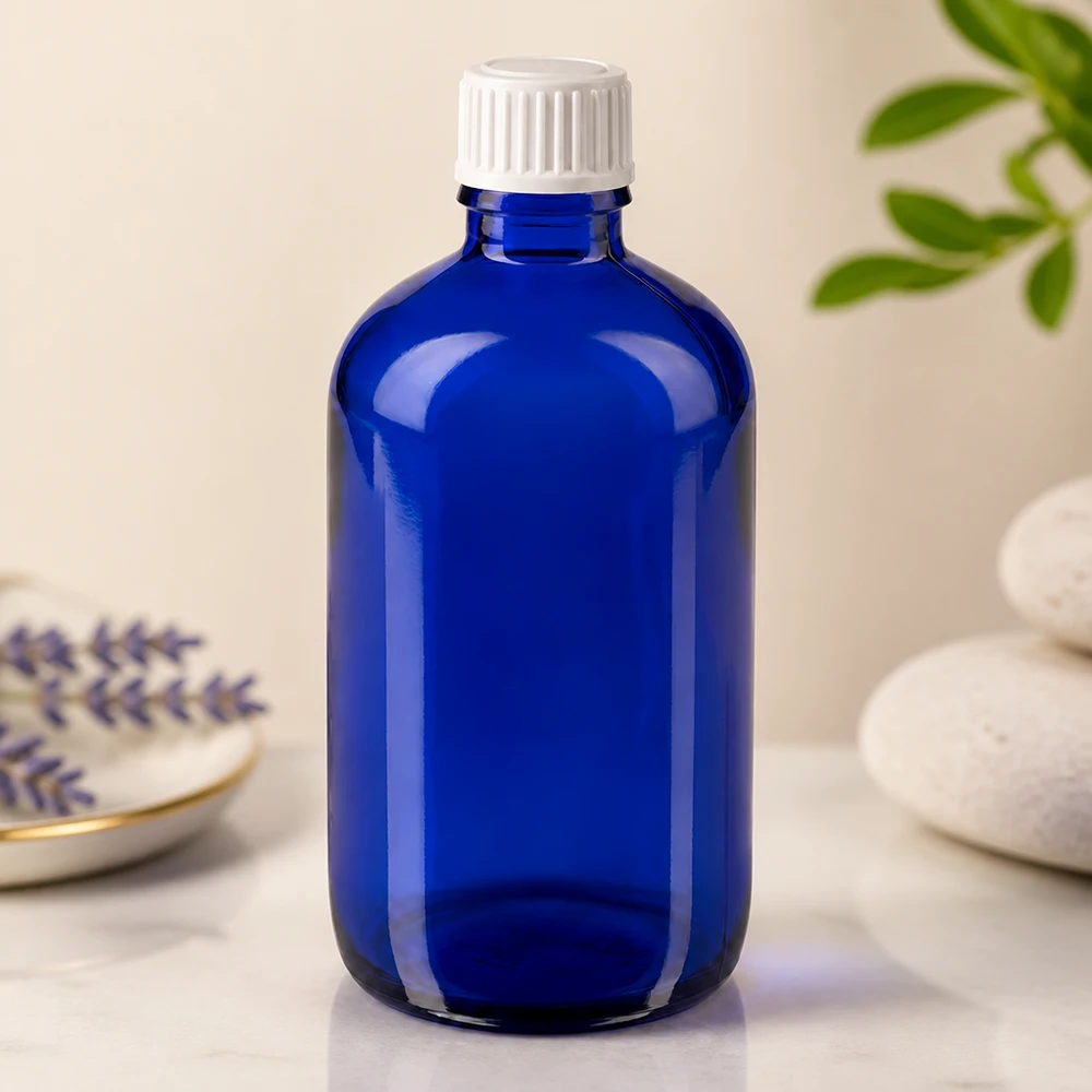 Apteekkipullo sininen 100ml kierrekorkki valkoinen standardi Sininen 100 ml:n lasipullo, jossa on valkoinen lapsiturvallinen korkki, marmoripinnalla laventelin vieressä