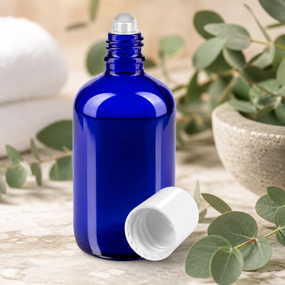 Apteekkipullo sininen 100ml roll-on korkki valkoinen 100 ml:n sininen roll-on-pullo, jossa on teräspallo ja valkoinen korkki eukalyptusoksien keskellä
