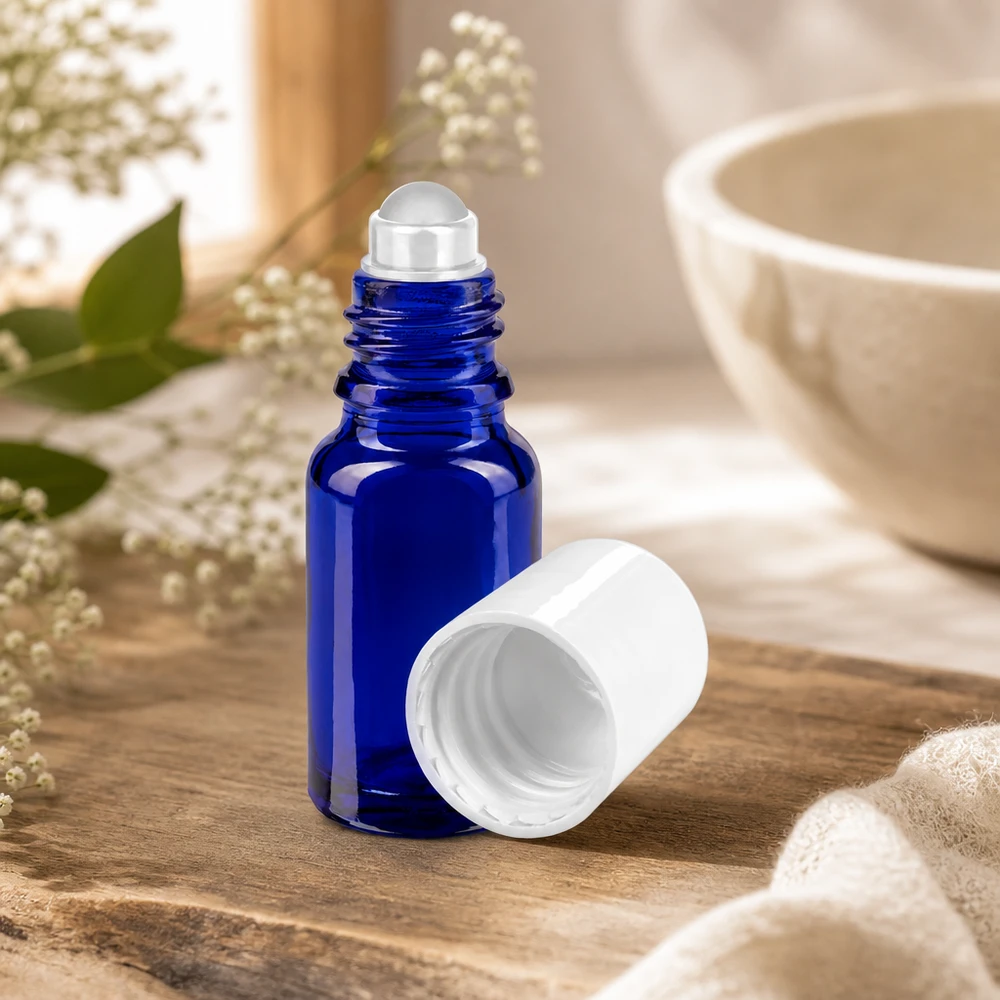 Apteekkipullo sininen 10ml roll-on korkki valkoinen Avoin koboltinsininen 10 ml:n roll-on-lasipullo, josta on irrotettu valkoinen korkki, puualustalla