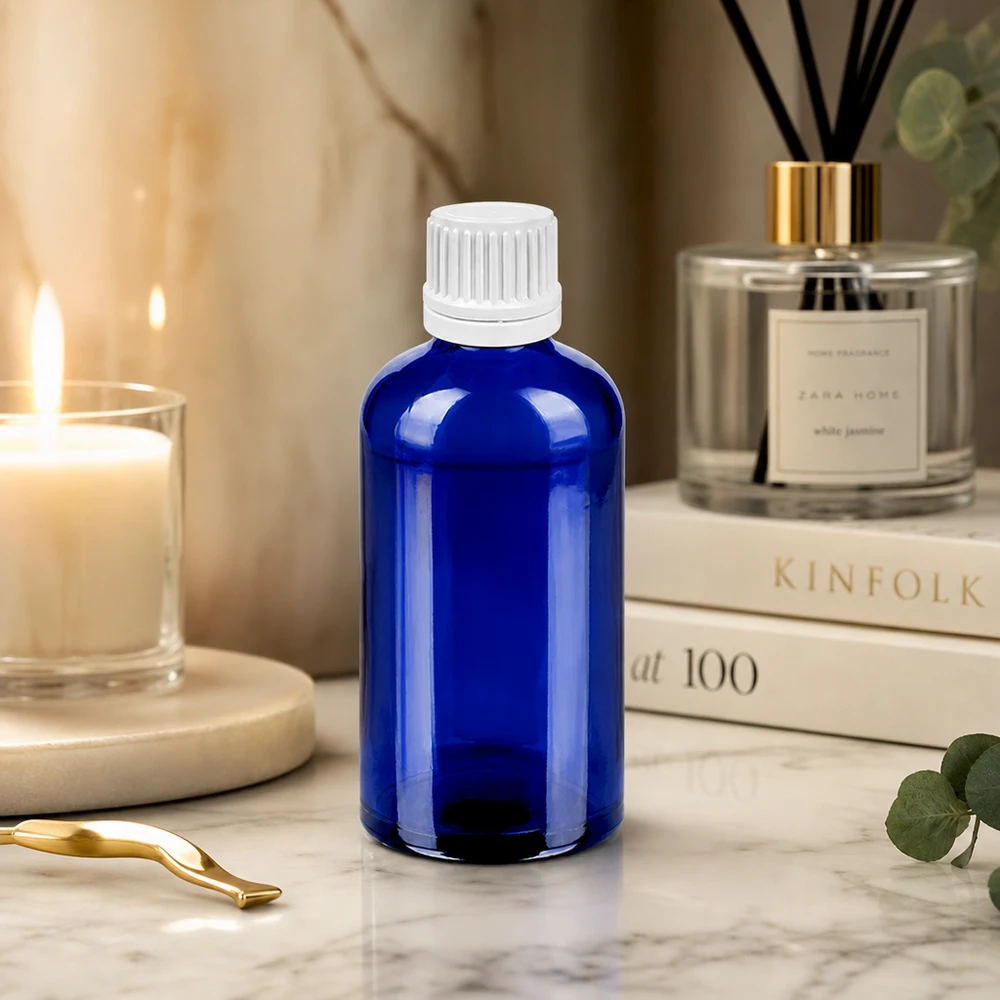 Tarkka tippapullo 100ml, joka on valmistettu kestävästä kobolttilasista ja jossa on valkoinen korkki valvottua annostelua varten.