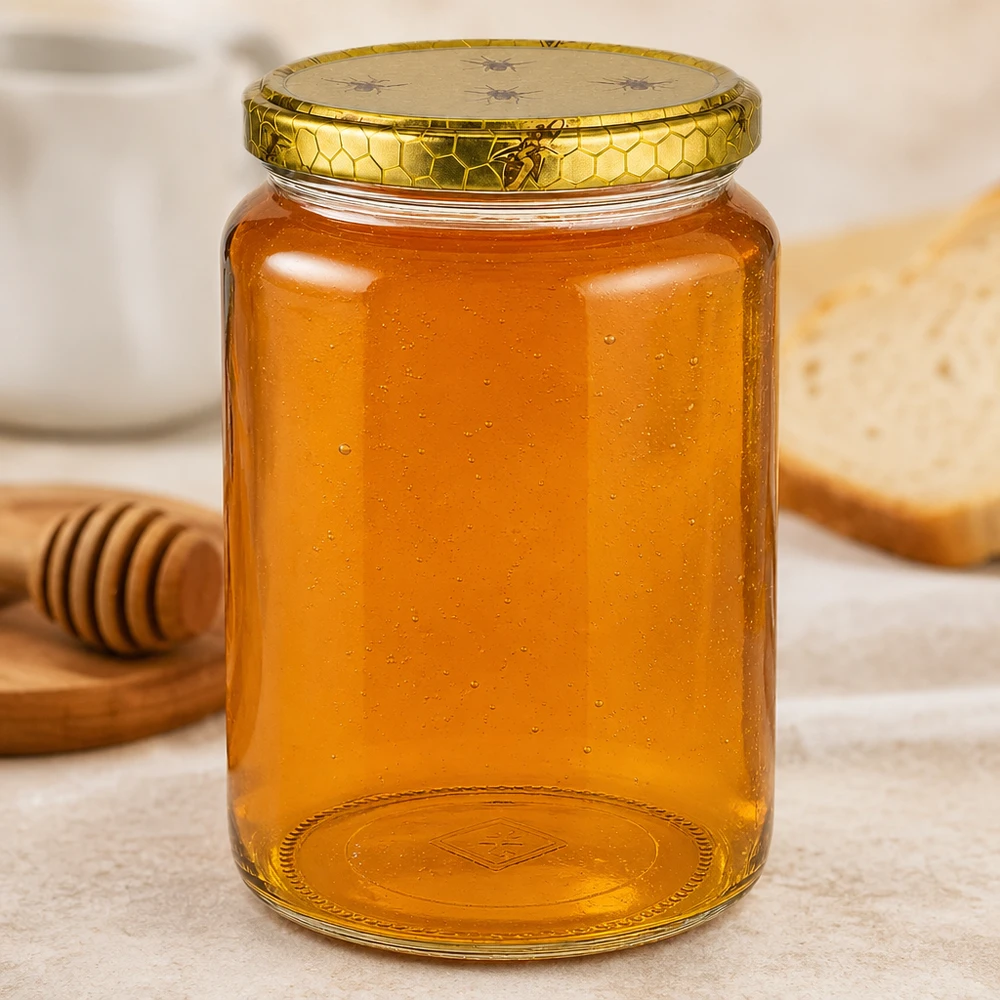 1000g Honigglas mit Bienenwabe Deckel BasicSeal UNiTWIST Suuri 1000g hunajapurkki, jonka pohjassa on kohokuviointi, vieressä hunaja tikku ja leipää puulevyllä Keittiö kohtaus Mehiläishoito tarvikkeet