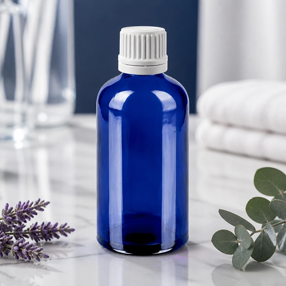 Tarkka tippapullo 100ml, valmistettu kestävästä sinisestä lasista, jossa on lapsiturvallinen valkoinen korkki.