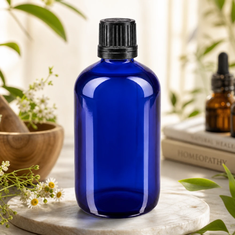 Apteekkipullo sininen 100ml ruuvikorkki musta valurengas sinetöityä sulkemista varten. Sininen 100 ml:n apteekkilasipullo, jossa on uurrettu musta korkki kamomillankukkien ja lääkekasvien keskellä