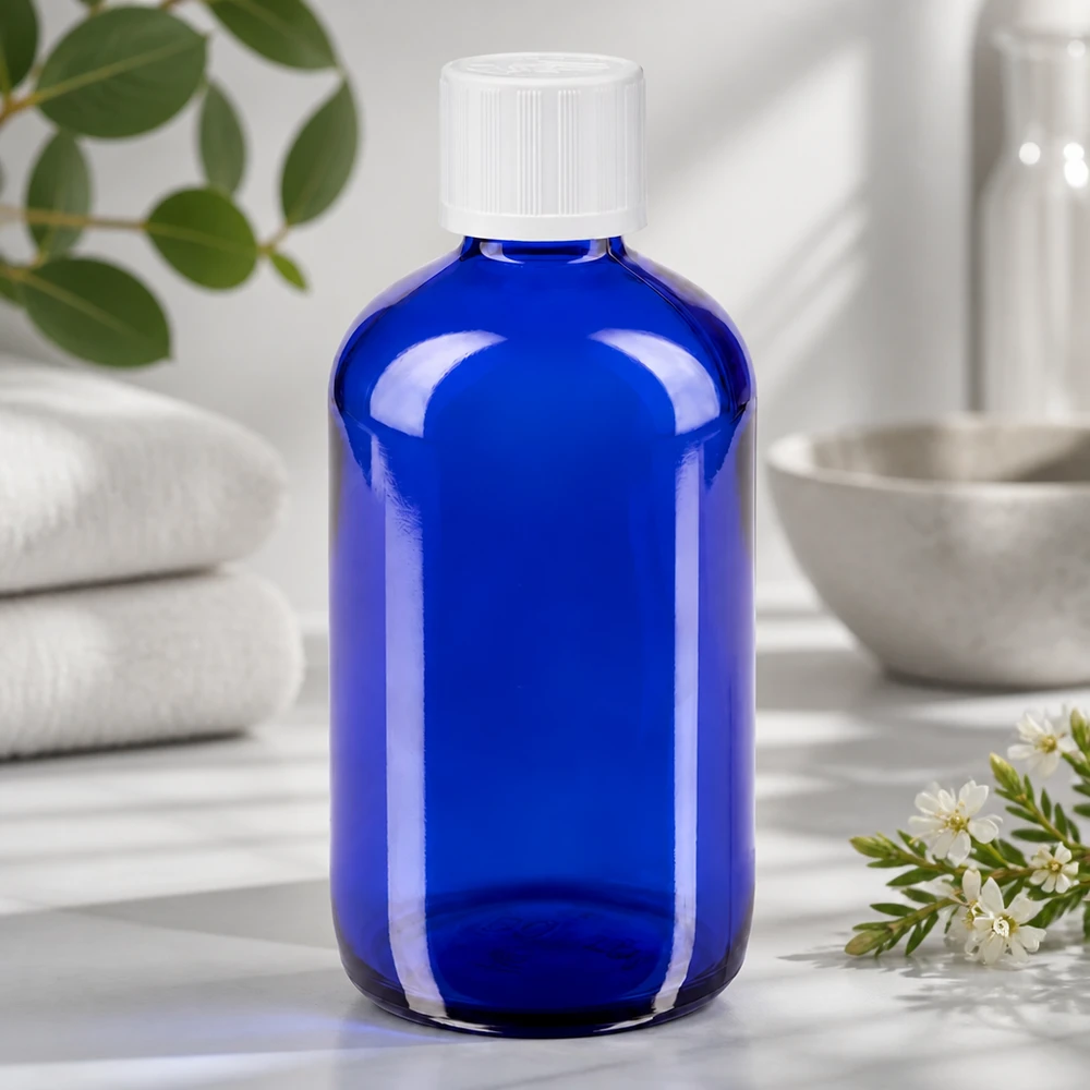 Läpinäkyvä sininen 100 ml:n lasipullo, jossa on valkoinen lapsiturvallinen korkki ja 1,2 mm:n tiputuskärki