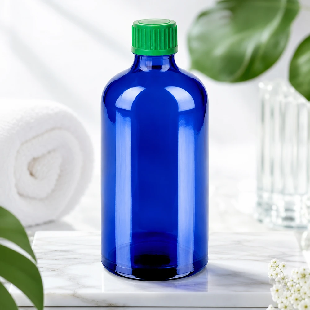 Laadukas BlueLine tippapullo 100ml tummansinisestä lasista, jossa on vihreä kierrekorkki UV-suojaa varten.