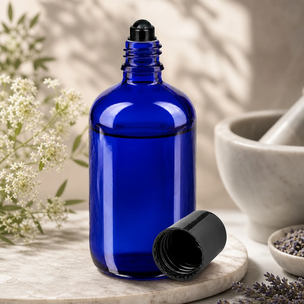 Apteekkipullo sininen 100ml roll-on korkki musta Koboltinsininen 100 ml:n lasipullo, jossa on musta rullapää, avattuna laventelikukkien ja morttelin vieressä