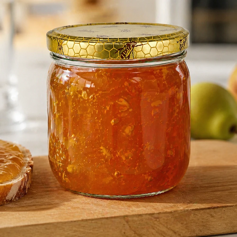 500g Honigglas mit Bienenwabe Deckel BasicSeal UNiTWIST 500 gramman hunajapurkki, jossa on hunajakennokansi ja joka on täytetty kultaisella hillolla, leivän ja vihreän omenan vieressä puulautasella.