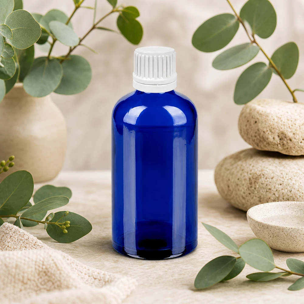 Tyylikäs sininen lasipullo 100ml valkoisella tiputuskorkilla - ihanteellinen kosmetiikkaan ja ihonhoitoon.