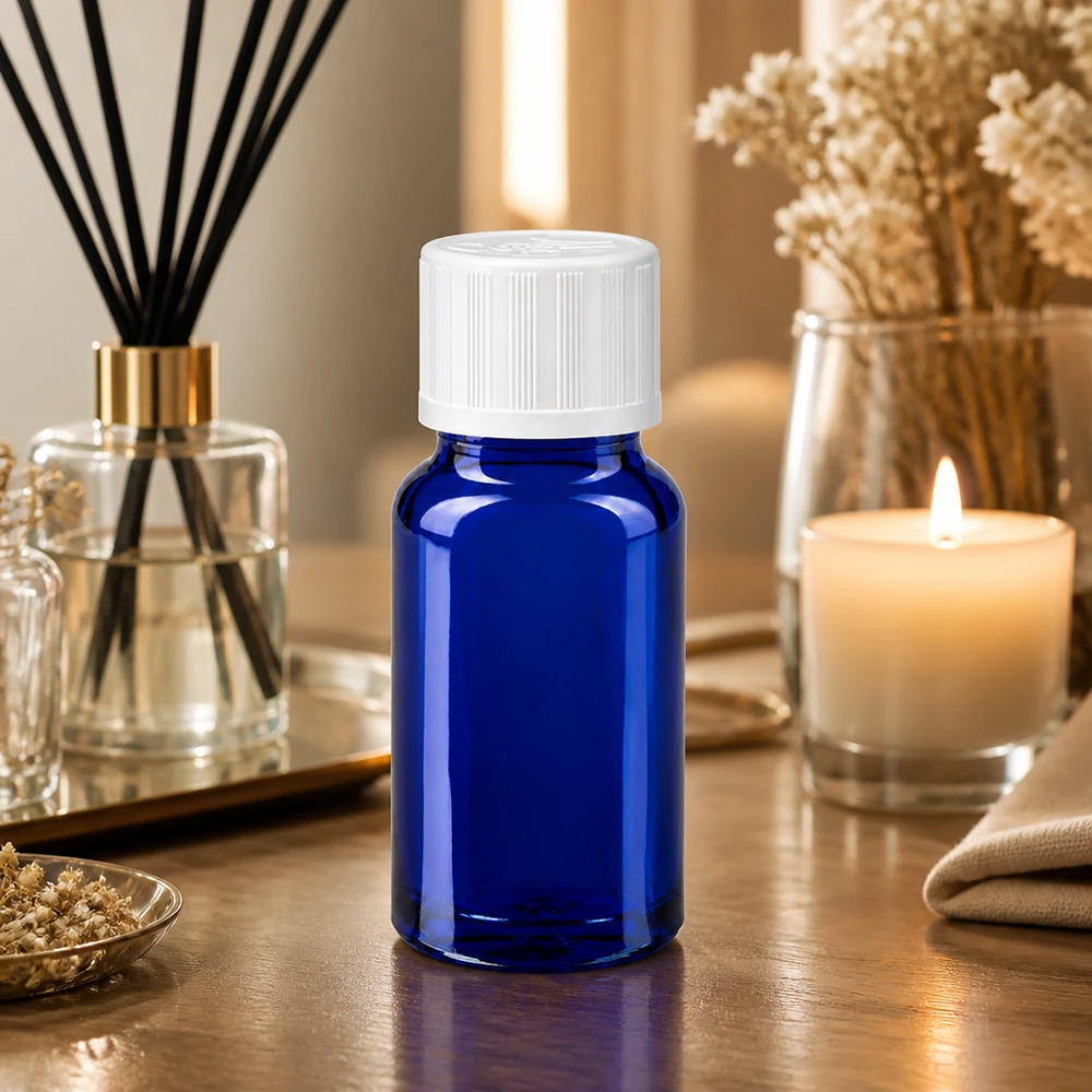 Pieni sininen lasipullo (10 ml), jossa on valkoinen kierrekorkki, puupöydällä huonotuoksun ja kynttilän vieressä