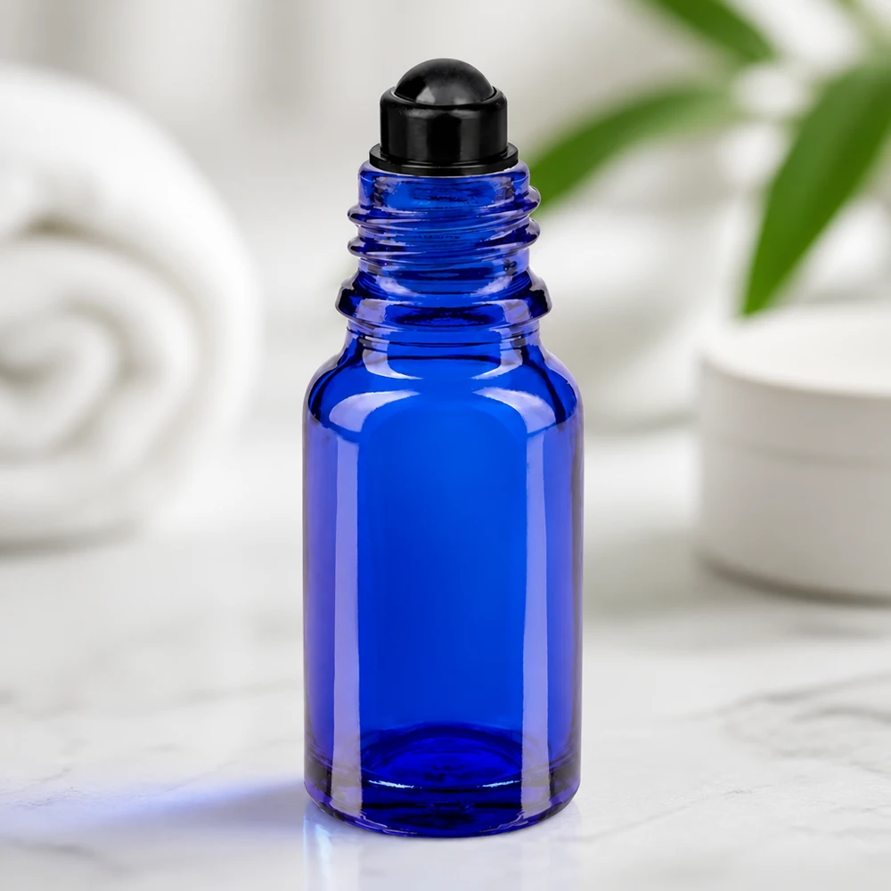 Apteekkipullo sininen 10ml roll-on korkki musta Sininen 10 ml:n lasipullo, jossa on musta rullapäällys, marmoripinnalla valkoista taustaa vasten