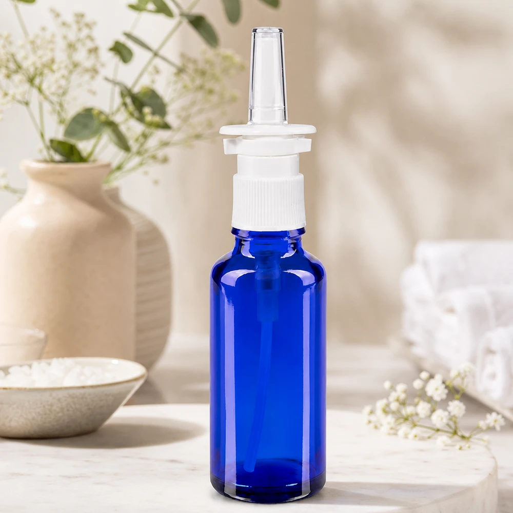Apteekkipullo sininen 30ml nenäsumutin valkoinen standardi Lähikuva: 30 ml:n nenäsumutepullo, koboltinsininen, valkoisella kierrekorkilla ja läpinäkyvällä muovikärjellä