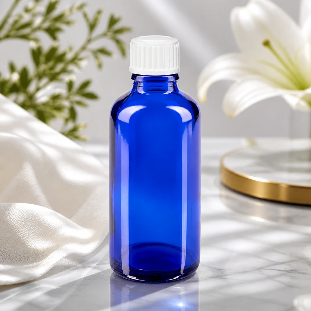 Apteekkipullo sininen 50ml ruuvikorkki valkoinen standardi Sininen 50 ml:n lasipullo, jossa on valkoinen kierrekorkki, valkoisen liljan vieressä marmoripinnalla