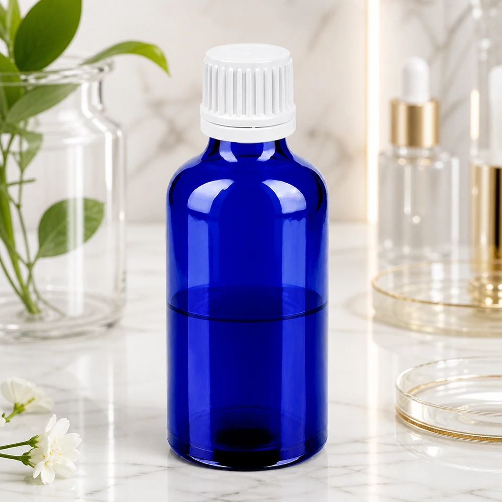 Pyöreä 50 ml:n lasipullo kirkkaan sinisellä ja käytännöllisellä valkoisella tiputuskorkilla.