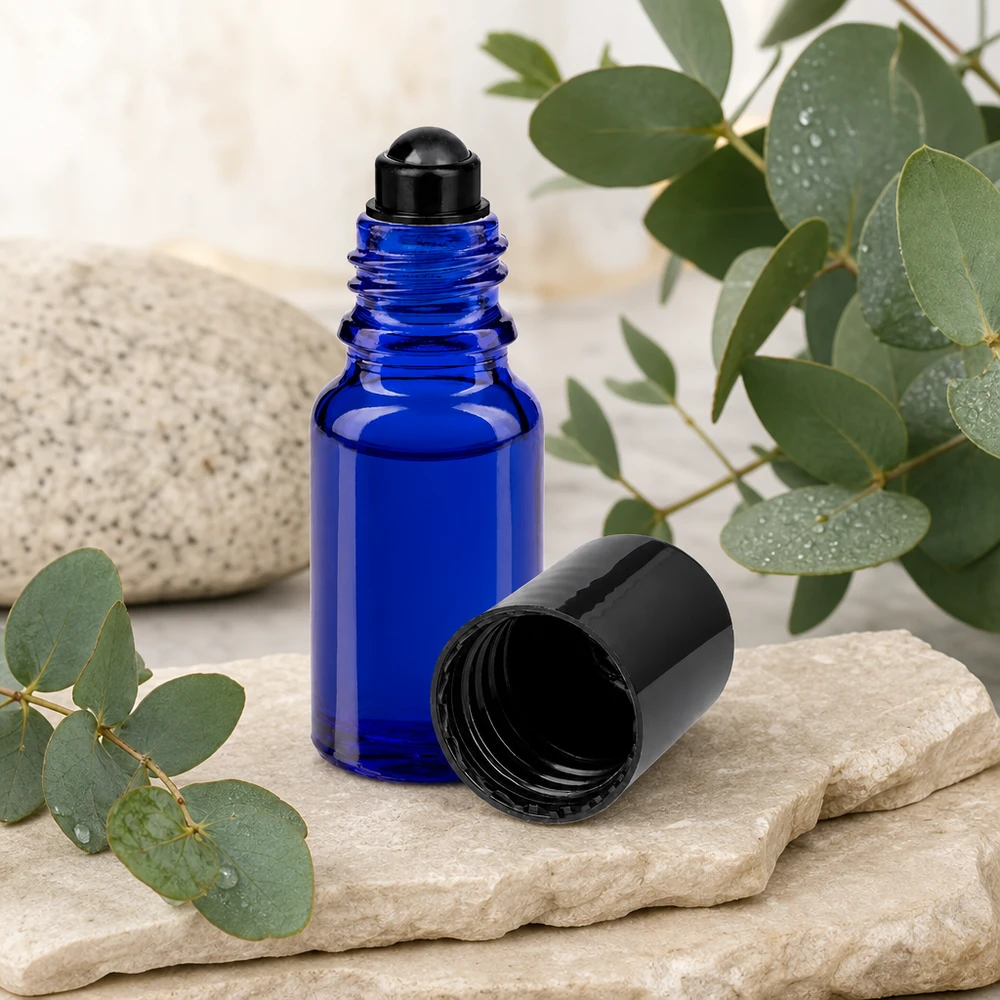 Apteekkipullo sininen 10ml roll-on korkki musta Sininen 10 ml:n ApoGlas-rullapullo, jossa on musta korkki, eukalyptusoksien vieressä luonnonkivellä