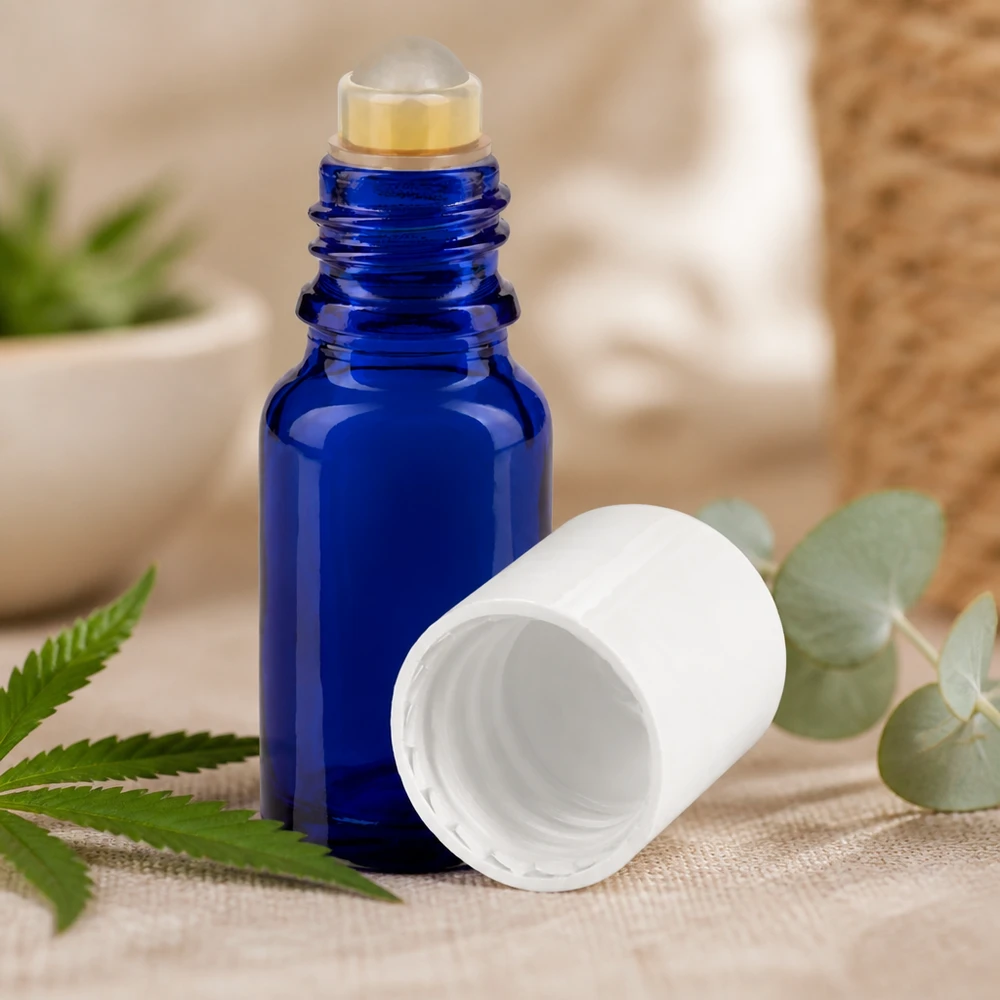 Apteekkipullo sininen 10ml roll-on korkki valkoinen Sininen 10 ml:n roll-on-pullo, jossa on valkoinen korkki, hampun- ja eukalyptuslehtien vieressä pellavakankaalla