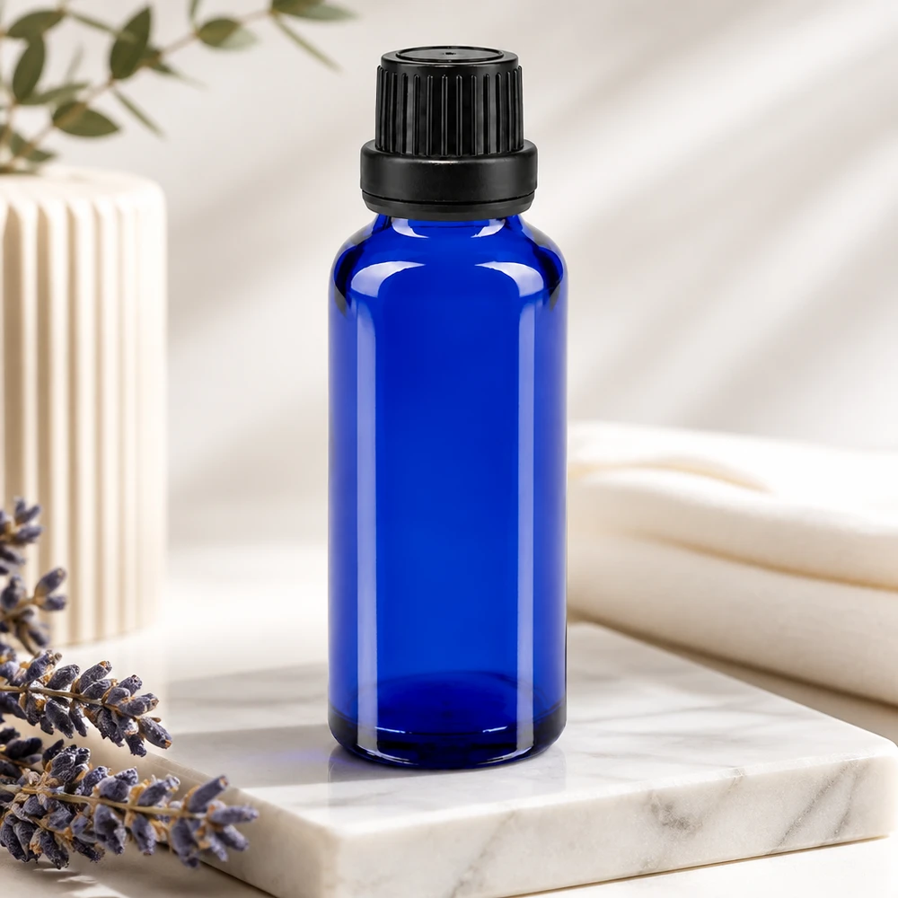 Sininen 30 ml:n ApoGlas-tiputuspullo, jossa on 2 mm:n suutin ja musta korkki, laventelin vieressä marmorilla