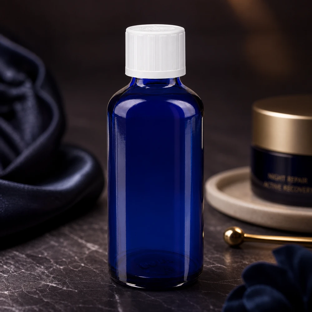 Koboltinsininen 50 ml:n apteekkipullo, jossa on valkoinen lapsiturvallinen korkki, tummalla marmoritaustalla