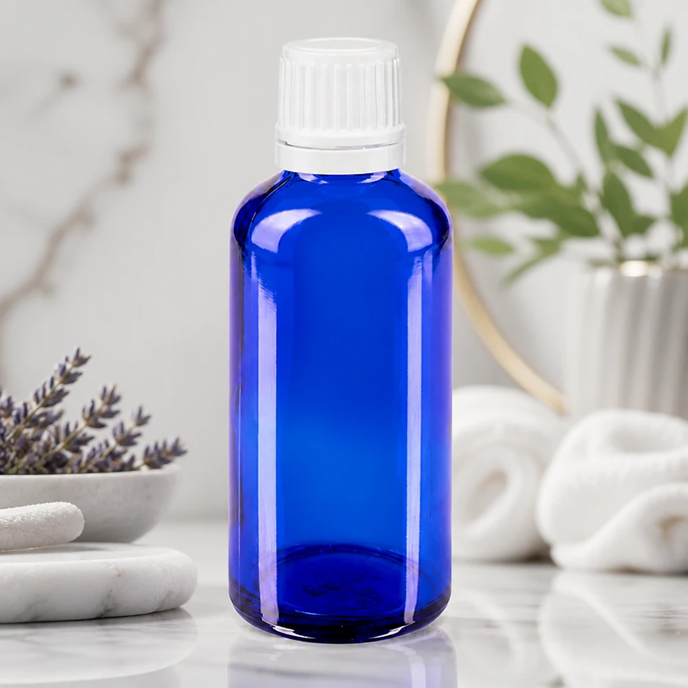 Sininen lasipullo (50 ml), jossa on valkoinen kierrekorkki, marmorilla laventelin vieressä