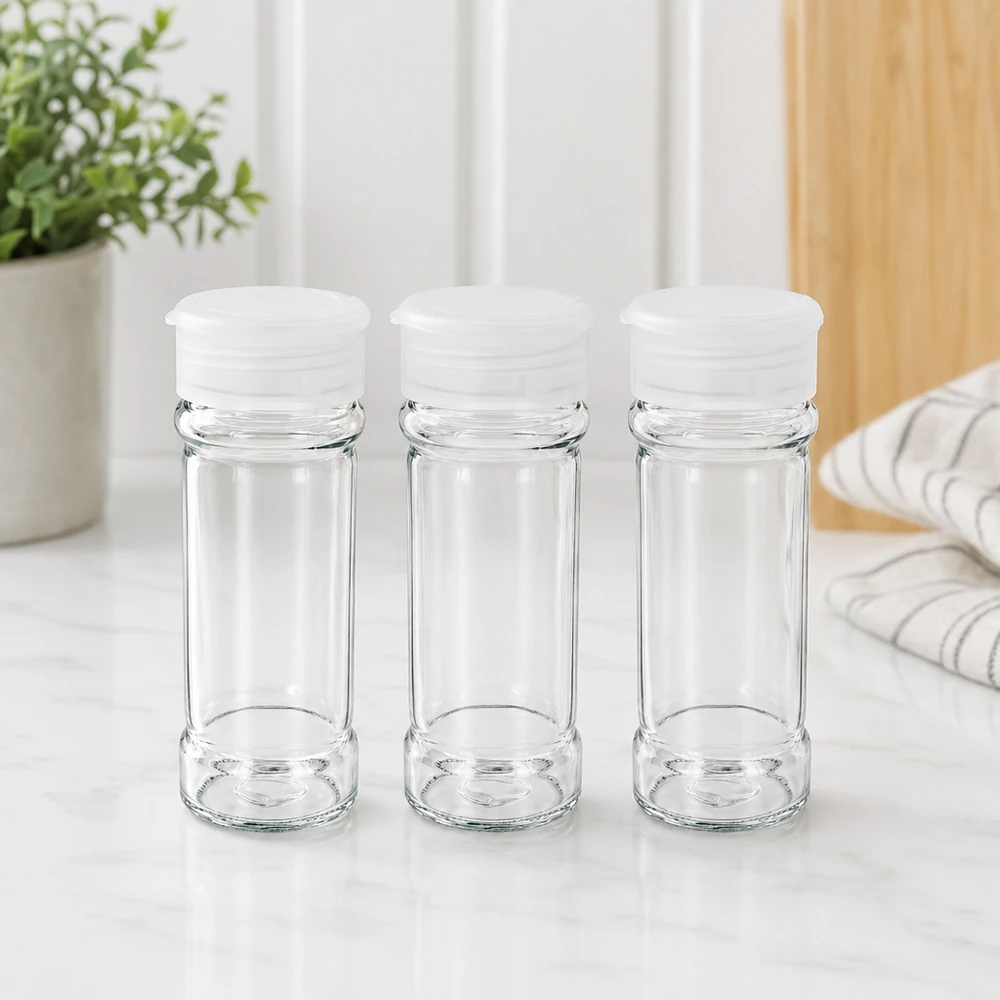 Suola-/maustepurkki 100 ml, valkoinen, ripottimella Kolme tyhjää, läpinäkyvää 100 ml:n maustepurkkia, joissa on valkoiset ripottelukannet, marmoripinnalla