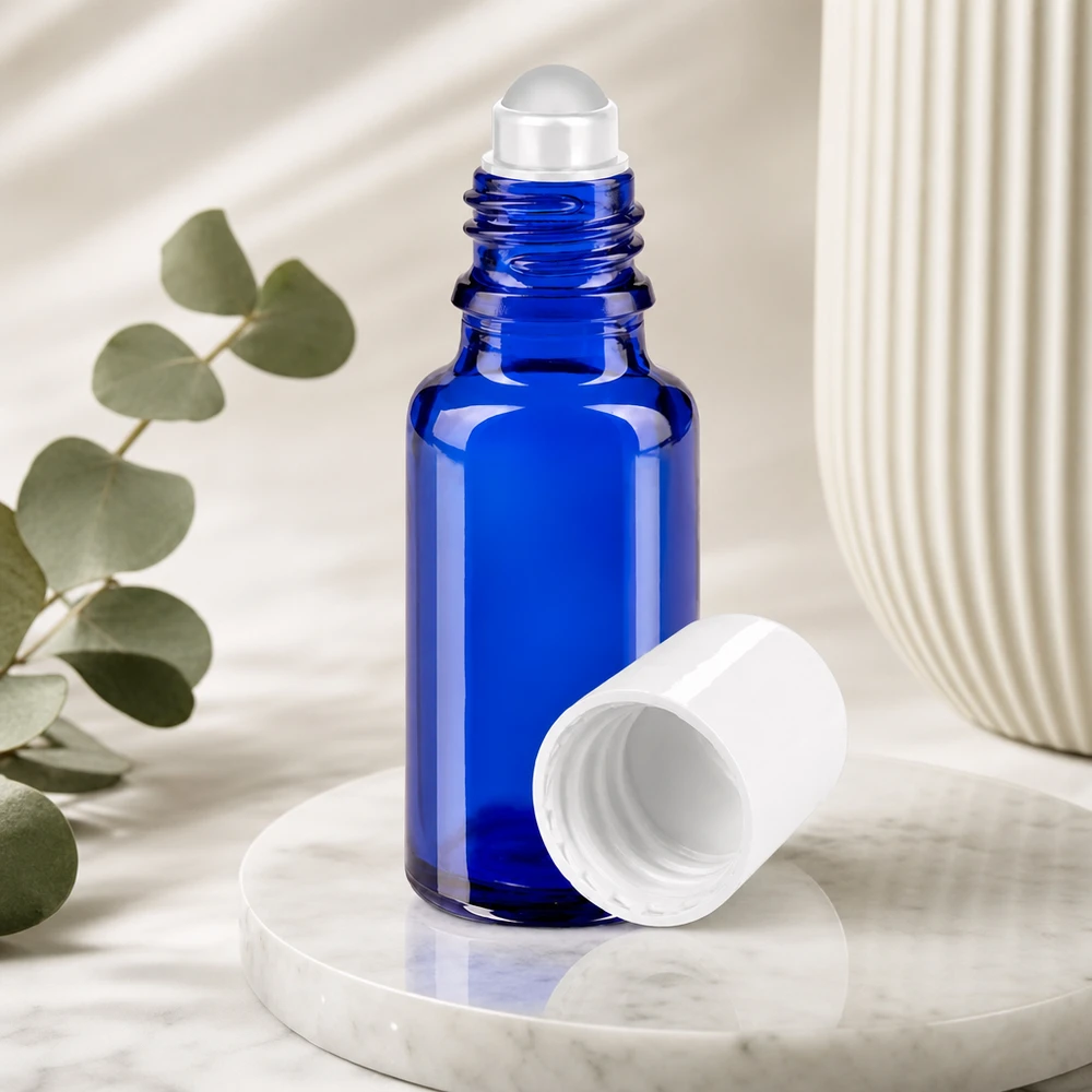 Apteekkipullo sininen 20ml roll-on korkki valkoinen Sininen 20 ml:n roll-on-pullo apteekkilasista, jonka valkoinen korkki on irrotettu, marmoripinnalla