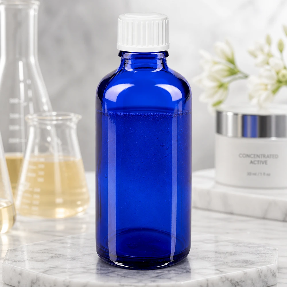 Koboltinsininen 50 ml:n lasipullo, jossa on valkoinen kierrekorkki, laboratoriopullon ja ihonhoitovoiteen vieressä