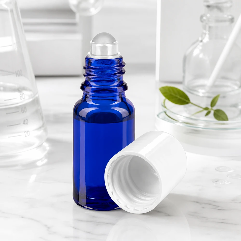 Apteekkipullo sininen 10ml roll-on korkki valkoinen Koboltinsininen 10 ml:n roll-on-pullo, jossa on läpinäkyvä lasipallo ja valkoinen korkki marmoritaustalla