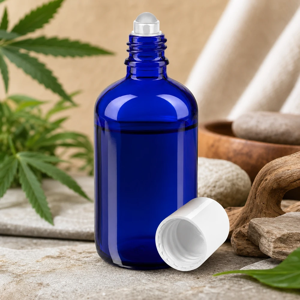 Apteekkipullo sininen 100ml roll-on korkki valkoinen Sininen 100 ml:n apteekkilasinen roll-on-pullo, jossa on luonnonkiviä ja kannabiksen lehtiä