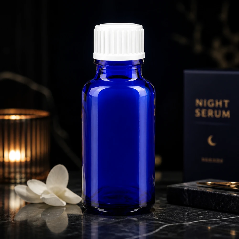 Apteekkipullo sininen 20ml ruuvikorkki valkoinen standardi Koboltinsininen 20 ml:n lasipullo valkoisella korkilla Night Serum -pakkauksen vieressä tummalla taustalla