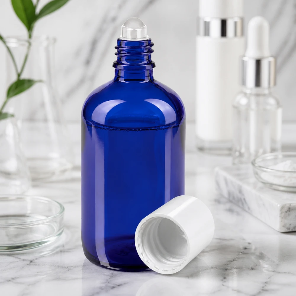 Apteekkipullo sininen 100ml roll-on korkki valkoinen Sininen 100 ml:n lasipullo, jossa on rullapää ja valkoinen korkki, marmoripinnalla