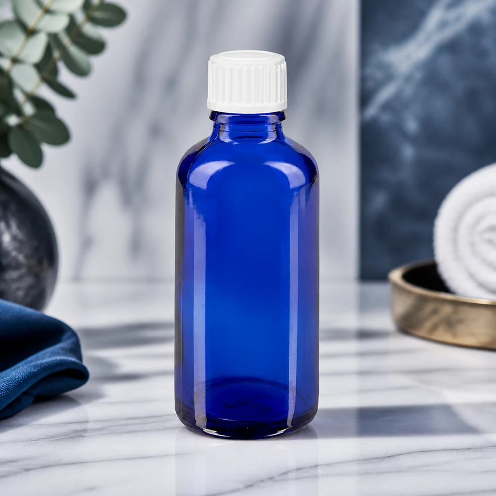 Koboltinsininen 50 ml:n STD-tiputuspullo ApoGlas-lasista, valkoisella korkilla, marmoripinnalla