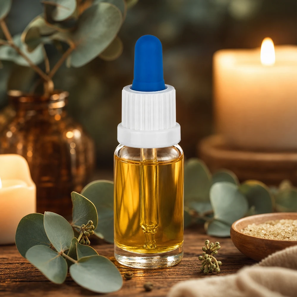 Pieni 10 ml:n pipettipullo, jossa on kullanväristä öljyä, valkoinen korkki ja sininen kumipallo, puupöydällä