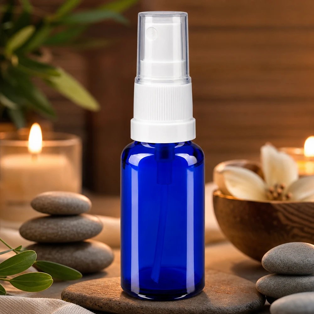 Sininen 20 ml:n apteekkilasinen suihkepullo, jossa on valkoinen pumppusuihkutin, wellness-spa-tunnelmassa kynttilöiden kera