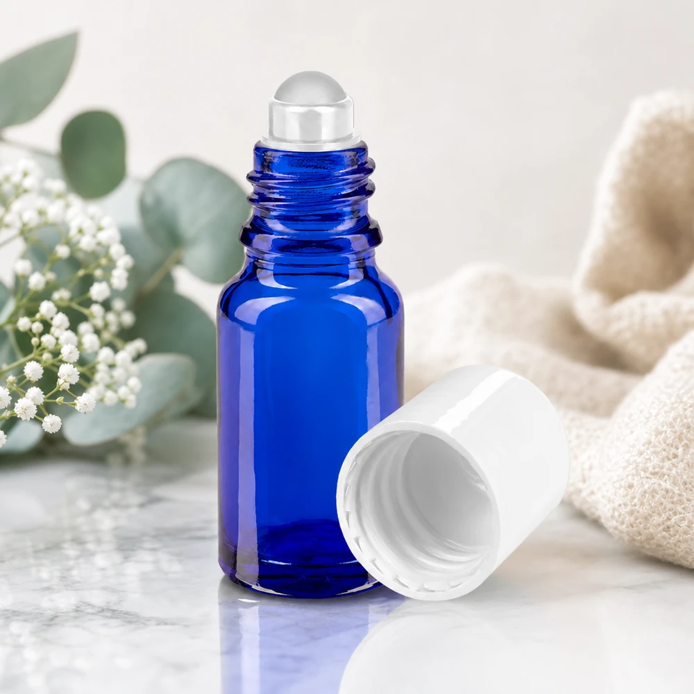 Apteekkipullo sininen 10ml roll-on korkki valkoinen Koboltinsininen 10 ml:n apteekkilasinen roll-on-pullo, jossa on läpinäkyvä lasipallo marmoripohjalla