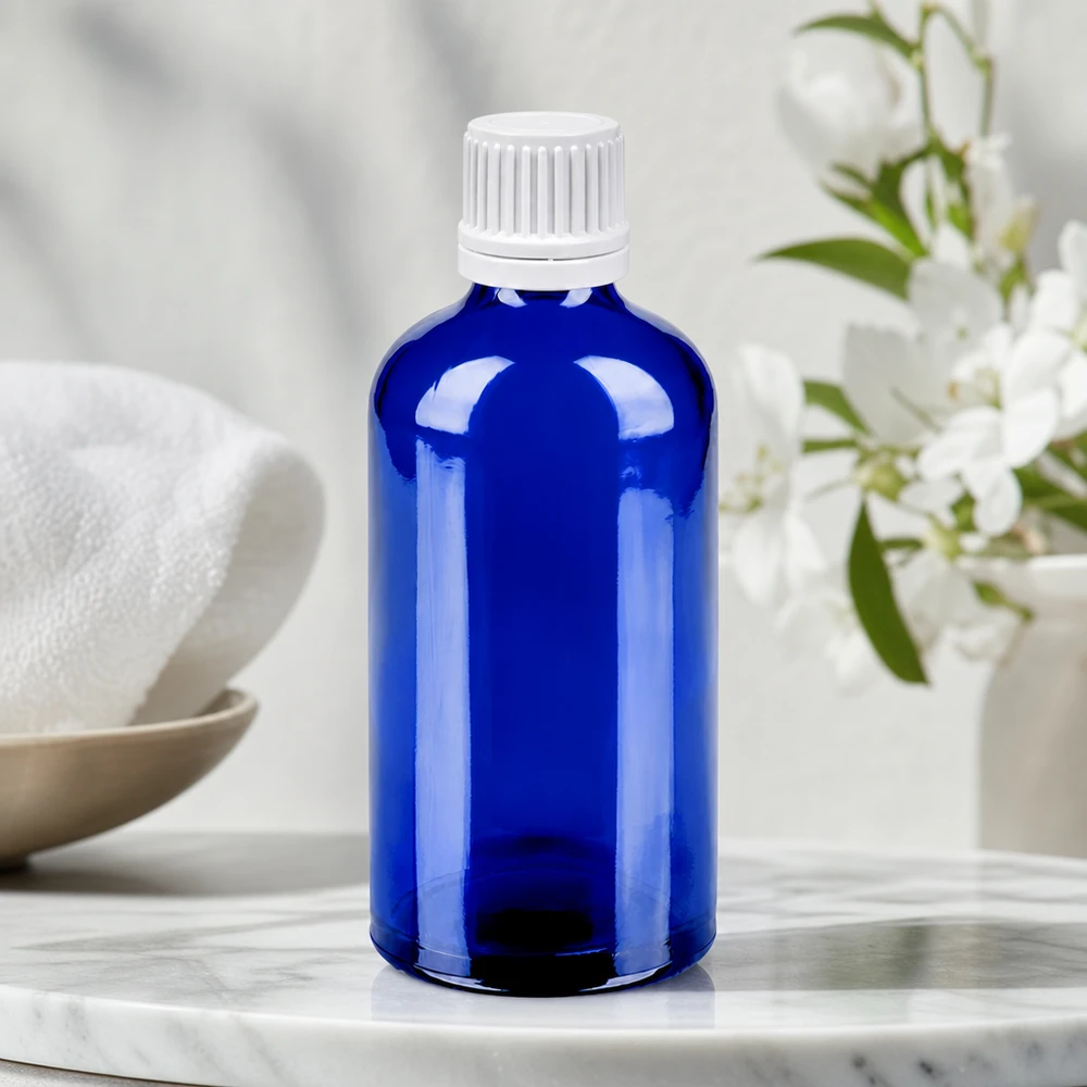 Kompakti 100 ml:n kirkkaan sininen lasipullo, jossa on tippumaton valkoinen korkki tarkkaa annostelua varten.