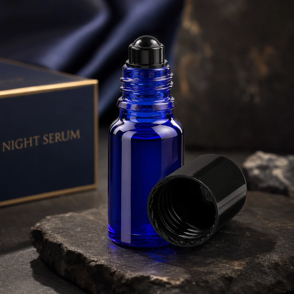 Tummansininen 10 ml:n ApoGlas-rullapullo, jonka musta korkki on auki, liuskekiven päällä Night Serum Boxin edessä