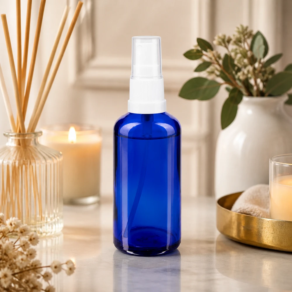 50 ml:n sininen apteekkilasinen suihkepullo, jossa on läpinäkyvä pumppupää, spa-tyylisessä ympäristössä