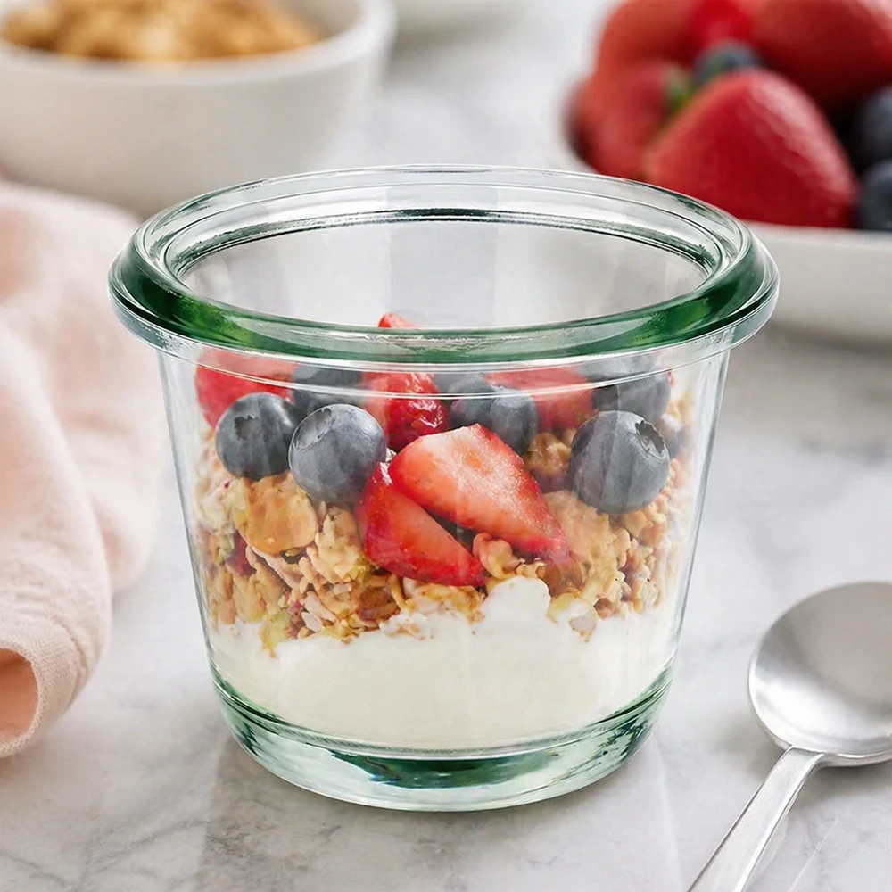 80ml Gughugelpurkki WECK RR60 täydellinen 80ml Gughugelpurkki WECK RR60 WECK Gourmet-purkki RR60 80ml murokulhona, jossa on jogurttimuroja ja tuoreita marjoja keittiön työtasolla.