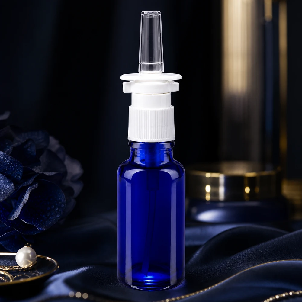 Apteekkipullo sininen 20ml nenäsumutinkorkki valkoinen std. 20 ml:n sininen nenäsumutepullo apteekkilasista, jossa on valkoinen pumppumekanismi silkkikankaalla