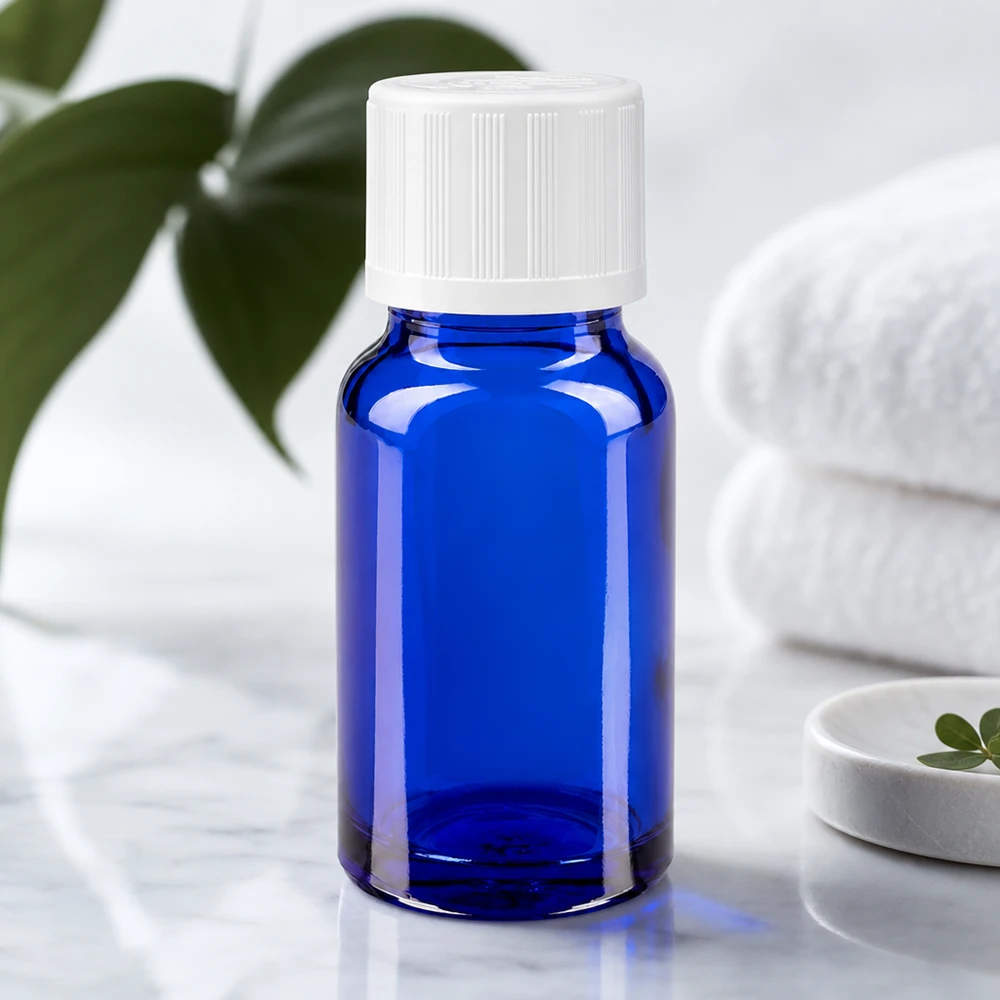 Apteekkipullo sininen 10ml tippapullon korkki valkoinen lapsiturvallinen standardi 10 ml:n sininen apteekkilasi, jossa on valkoinen lapsiturvallinen korkki, marmorilla taitettujen pyyhkeiden vieressä