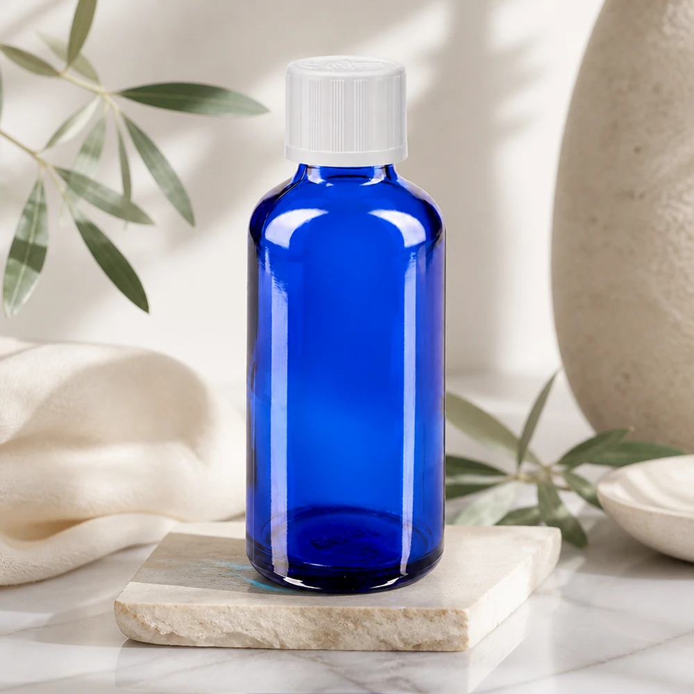 Apteekkipullo sininen 50ml tippapullon korkki valkoinen lapsiturvallinen standardi Sininen 50 ml:n lasipullo, jossa on valkoinen kierrekorkki, marmorikiven päällä vaaleassa luonnollisessa ympäristössä