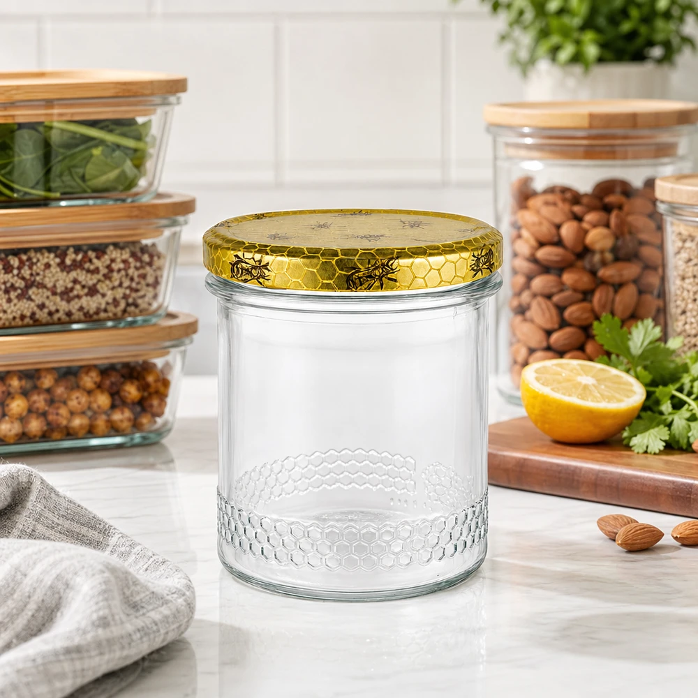 560g Honigglas + BasicSeal Deckel Bienenwabe UNiTWIST 400 ml:n hunajapurkki kultaisella hunajakennokannella keittiön työtasolla, taustalla säilytyspurkkeja pähkinöillä